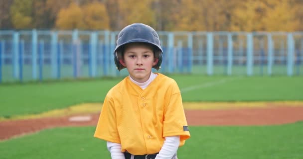 Porträtt av en pojke basebollspelare på en suddig bakgrund, smeten håller ett basebollträ i händerna och tittar på kameran, 4k slow motion. — Stockvideo