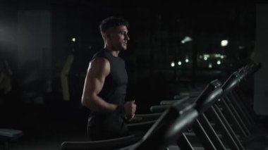 Atletik koşucu, koşu bandında koşan bir adam, spor salonunda aerobik egzersiz ve dayanıklılık eğitimi, gece antrenmanında motivasyon, 4k ağır çekim..