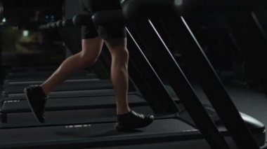 Atletik koşucu, koşu bandında koşan bir adam, spor salonunda aerobik egzersiz ve dayanıklılık eğitimi, gece antrenmanında motivasyon, 4k ağır çekim..
