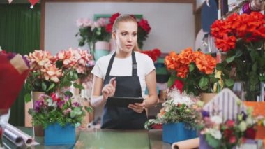 Çiçekçi kadın bir çiçekçide envanter tutar, bir kadın çiçekçi dükkanındaki çiçek ve bitkileri saymak için ekran tableti kullanır..