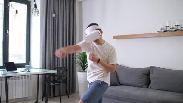 Junger Mann mit futuristischer Virtual-Reality-Brille spielt Kampfspiel-Simulator, Sport mit moderner Technologie in Selbstisolation, Online-Sporttraining im Wohnzimmer, 4k Zeitlupe. — Stockvideo