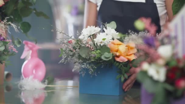 花屋の女性は箱の中の花の花束を飾る、花や植物の店で働く陽気な女性、多色のインテリア. — ストック動画