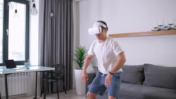 Fütüristik sanal gerçeklik gözlüklü adam ısınma egzersizleri yapıyor, spor yapıyor, modern teknoloji kullanarak kendini izole ediyor, oturma odasında online spor eğitimi alıyor.. — Stok video
