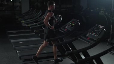 Atletik koşucu, koşu bandında koşan bir adam, spor salonunda aerobik egzersiz ve dayanıklılık eğitimi, gece antrenmanında motivasyon, 4k ağır çekim..