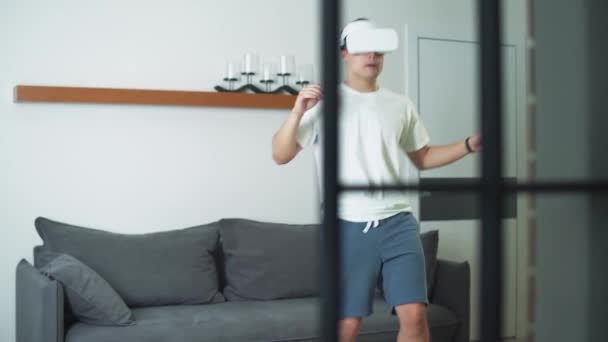 Mann in futuristischer Virtual-Reality-Brille treibt Sport und spielt mit einem virtuellen Fußball, Sport mit moderner Technologie in Selbstisolation. — Stockvideo