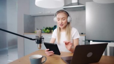 Kadın streamer sosyal ağlar için canlı bir podcast yapıyor, mutfakta otururken uzaktan çalışıyor, dizüstü bilgisayar ve tablet kullanıyor, koronavirüs salgını bağlamında çalışıyor, karantina.