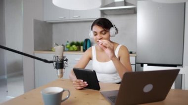 Kadın video blogcusu sosyal ağlar için canlı bir podcast yapıyor, mutfakta otururken uzaktan çalışıyor, dizüstü bilgisayar ve tablet kullanıyor, koronavirüs salgını bağlamında çalışıyor, karantina.