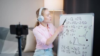 Kadın kimya öğretmeni çevrimiçi bir ders veriyor, akıllı telefon, okul dersleri ve koronavirüs salgını bağlamında uzaktan çalışma kullanarak öğrenme sürecinin canlı yayını.