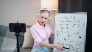 Kadın kimya öğretmeni çevrimiçi bir ders veriyor, akıllı telefon, okul dersleri ve koronavirüs salgını bağlamında uzaktan çalışma kullanarak öğrenme sürecinin canlı yayını.