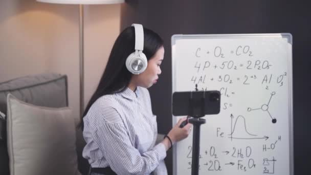 Aasian naiskemian opettaja tekee oppitunnin verkossa, suorana lähetyksenä oppimisprosessista älypuhelimella, koulun oppitunneilla ja etätyöllä koronaviruksen pandemian yhteydessä, nainen — kuvapankkivideo