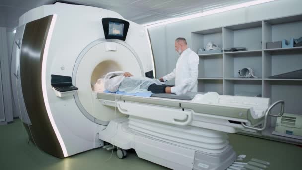 Ressonância magnética no hospital moderno, homem adulto médico realiza um exame tomográfico magnético de uma mulher jovem, MRI, tecnologias modernas em medicina. — Vídeo de Stock