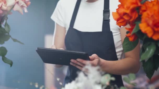 꽃 가게에서 꽃 장사를 하는 여성, 화방에서 꽃 과 식물 의수를 계산하기 위해 스크린 태블릿을 사용하는 여성. — 비디오