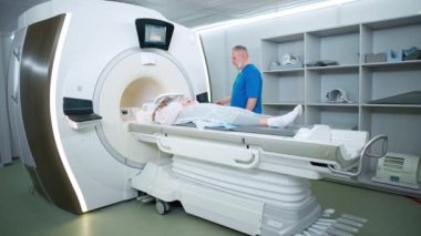 Modern hastanede manyetik rezonans görüntüleme, yetişkin erkek doktor genç bir kadının manyetik tomografi incelemesini yapıyor, MRI, modern tıp teknolojileri..