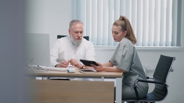 의료 전문가들은 환자를 치료하는 방법, 성인 남성 의사와 여성 간호사가 의료 문제에 관해 의사소통을 하고 스크린 태블릿을 사용하는 방법, 전문 의료진 이 일하는 곳 에서 — 비디오