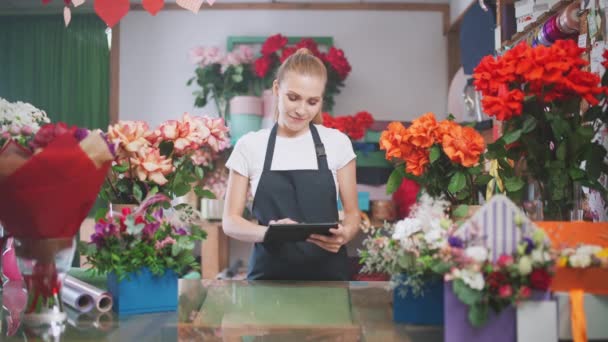 Floristin macht Inventur in einem Blumenladen, eine Frau zählt per Bildschirmtablette die Anzahl der Blumen und Pflanzen in einem Blumenladen. — Stockvideo