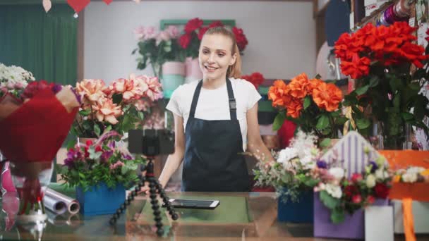 Blumenhändlerin diskutiert die Bestellung per Videoanruf, Smartphone im Blumenladen, Online-Arbeit, die Frau wählt Blumen für den Kunden, Live-Übertragung. — Stockvideo