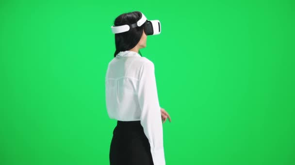Γυναίκα σε φουτουριστικό γυαλιά εικονικής πραγματικότητας ελέγχει την εικονική διεπαφή με μια κίνηση των χεριών, πρότυπο σε ένα πράσινο φόντο, chromakey, πίσω όψη. — Αρχείο Βίντεο