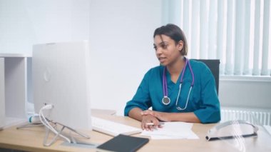 Kadın doktor iş yerinde oturur ve hastayla görüntülü görüşme yoluyla iletişim kurar. Uzmanların ve doktorların uzak konferansı online, modern hastane....