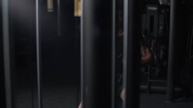 Spor salonundaki kürek çekme makinesinde taş kaldıran atletik adam, blok aleti ve spor aleti eğitimi, gece vakti, 4K ağır çekim.