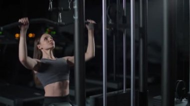 Spor salonunda kadın kaldırma blokları raf makinesinde, blok aygıtı ve spor aletleri üzerinde güç eğitimi, gece eğitimi, 4k ağır çekim.