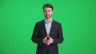 Takım elbiseli bir muhabir kameraya bakar ve konuşur, yeşil bir zeminde durur, TV haber ajansları için bir şablon, iş yerinde bir gazeteci, kromakey.