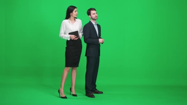 Pareja de jóvenes en trajes, hombre y mujer de pie en el espacio verde de la cromakey, viendo y discutiendo cosas simples, cromakey plantilla. — Vídeos de Stock