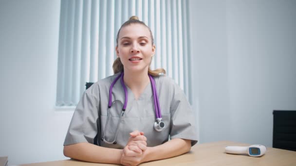 Žena lékař sedí na pracovišti, dívá se do kamery a komunikuje s pacientem prostřednictvím videohovoru, vzdálené konference lékařského specialisty a lékařů on-line, moderní nemocnice. — Stock video