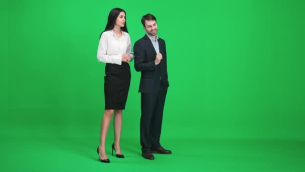 Молодой человек и женщина в костюмах стоят в зеленом пространстве хромаки, обсуждают темы, глядя перед собой, шаблон на зеленом фоне. — стоковое видео
