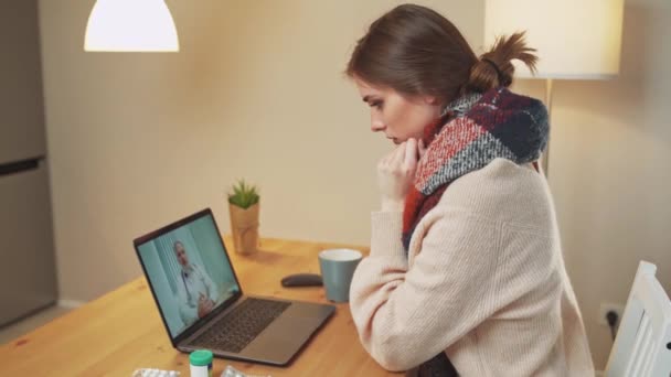 Donna in isolamento comunica con un medico tramite videochiamata utilizzando un computer portatile, un paziente consulta un medico online durante la quarantena, pandemia di coronovirus. — Video Stock