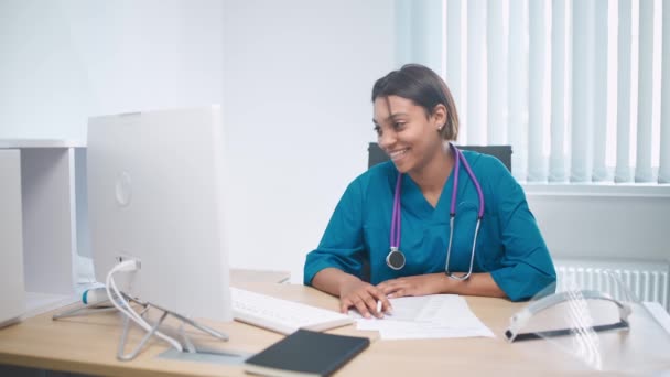 Medico femminile si siede sul posto di lavoro e comunica con la paziente tramite videochiamata, conferenza remota di medici specialisti e medici online, ospedale moderno. — Video Stock