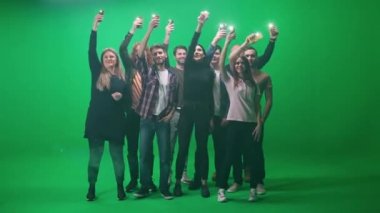 Farklı yaşlarda bir grup insan konserde dans ediyor, elinde flaş ışığı olan akıllı telefonlar, müzik konserindeki hayranlar, yeşil bir arka planda dans edip kollarını sallıyorlar.
