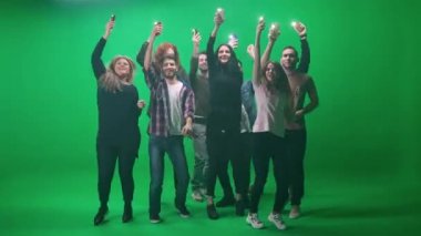 Farklı yaşlarda bir grup insan konserde dans ediyor, ellerinde flaş ışığı olan akıllı telefonlar tutuyorlar, müzik konserindeki hayranlar yeşil arka planda zıplıyor ve dans ediyorlar, bir kromakey şablonu..