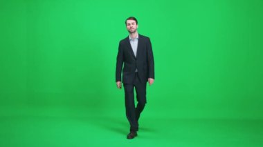 Yoldan geçen takım elbiseli adamlar yeşil arka planda yürürler, mutlu bir adam yaklaşır ve kameraya bakar, gülümseyen adam, kromakey şablonu.