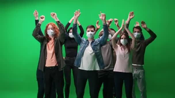 Crowd of people of different ages dancing at a concert, people in protective medical masks, fans at a music concert, they dance and swing their arms on a green background, a chromakey template, event — Stock Video
