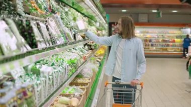 Vejetaryenlik, genç bir adam sebzeleri hipermarketten seçer ve satın alır, organik ürünler satan bir dükkandan sağlıklı yiyecekler alır, sebzeleri alışveriş arabasına koyar..