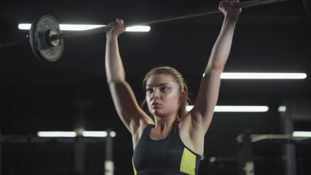 Atletisch vrouwtje doet oefeningen met lange halter, tilt lange halter en doet gewichtstraining in de sportschool. — Stockvideo