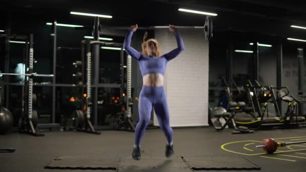 Atletisch vrouwtje doet oefeningen met lange halter, tilt lange halter en doet zware gewichten training in de sportschool. — Stockvideo