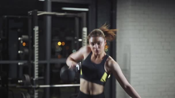 Mujer atlética realiza ejercicios con pesas kettlebells, levanta pesas y hace entrenamiento crossfit kettlebell en el gimnasio. — Vídeo de stock