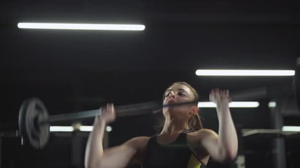 Atletisch vrouwtje doet oefeningen met lange halter, tilt lange halter en doet gewichtstraining in de sportschool. — Stockvideo