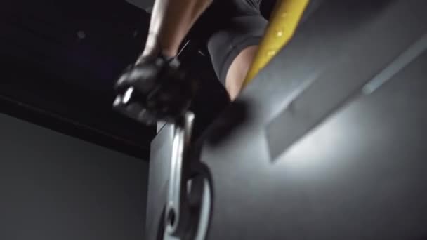 Ciclo de entrenamiento en una bicicleta de giro, el hombre realiza entrenamiento de resistencia aeróbica en los simuladores de ciclo, vista del pie. — Vídeo de stock