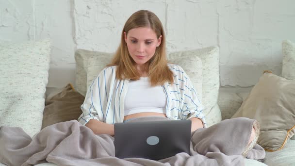 Rutinmässig, kvinnlig sitter på soffan hemma och arbetar med en bärbar dator, chef på ett distansarbete under självisolering i karantän, kvinna gör en bra affär, positiva känslor. — Stockvideo