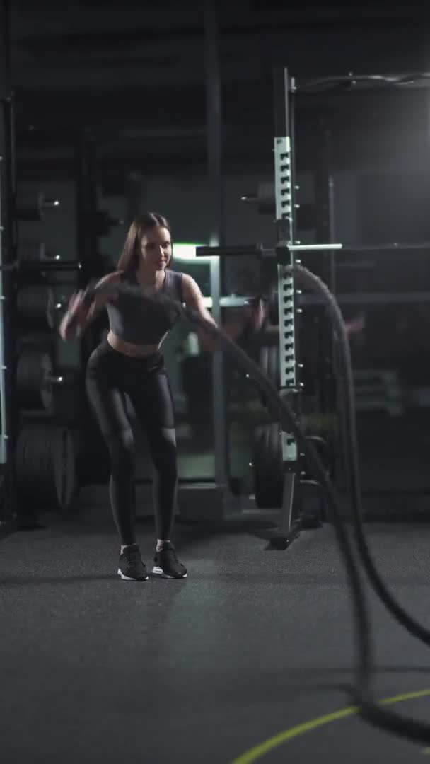 Γυναίκα εκτελεί ασκήσεις με σχοινιά μάχης, προπόνηση αντοχής στο γυμναστήριο, 4k κάθετη βίντεο. — Αρχείο Βίντεο