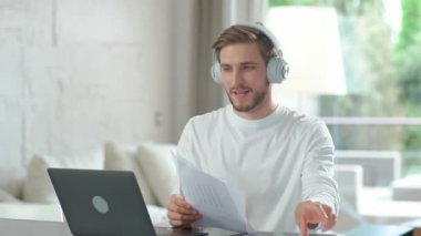 Kafkasyalı genç yönetici bilgisayarla iş arkadaşlarıyla görüntülü iletişim kuruyor. Karantinada kendini izole ederken uzaktan çalışan bir adam..