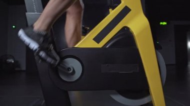 Bisiklet süren bir adam, spor salonundaki simülatörlerde aerobik dayanıklılık eğitimi, bisiklet eğitimi, ayak manzarası....