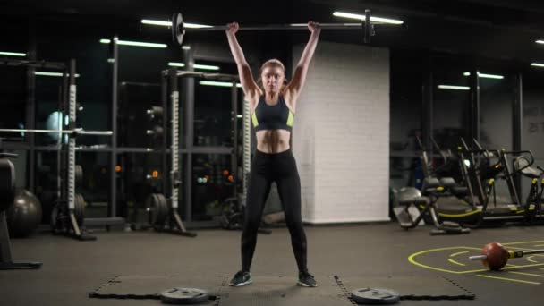 Stark atletisk kvinna utför övningar med skivstång, lyfter skivstång och tränar vikter i gymmet. — Stockvideo