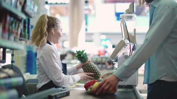 Groenten en fruit kopen in een supermarkt, wordt de man betaald bij de kassa van de supermarkt, jonge vrouw kassier op het werk in een biologische winkel. — Stockvideo