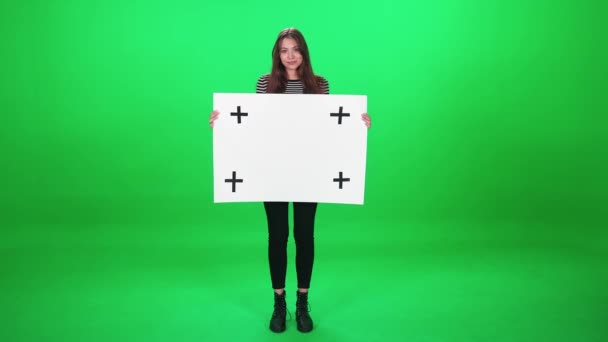 Protestní hnutí, aktivistka stojící na zeleném pozadí a držící plakát z bílého papíru, šablona, seriózní pohled na kameru na pozadí s klíčem chroma. — Stock video