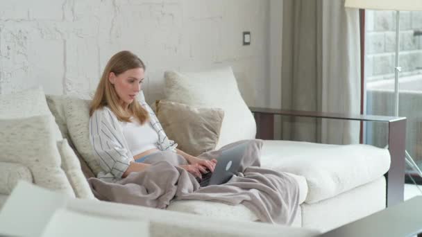 Konzentrierte Frau sitzt zu Hause auf der Couch und arbeitet mit Laptop, Manager während der Selbstisolierung in Quarantäne an einer Fernarbeit. — Stockvideo