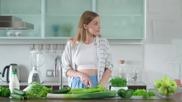 Kadın mutfakta salata hazırlıyor, otlar ve yeşil sebzeler kesiyor, mutfakta genç bir çift sağlıklı salata hazırlıyor, olumlu duygular besliyor.. — Stok video