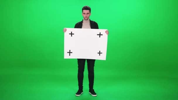 Protestní hnutí, muž aktivista stojící na zeleném pozadí a drží plakát z bílého papíru, šablona, seriózní pohled do kamery na pozadí s klíčem chroma. — Stock video